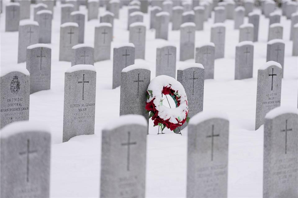 Ein schneebedeckter Kranz lehnt an einem Grabstein vor der Gedenkfeier zum Remembrance Day auf dem nationalen Soldatenfriedhof in Beachwood in Ottawa in Kanada.Justin Tang/The Canadian Press/AP/dpa