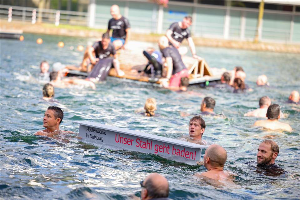 Ein symbolischer Stahlträger mit dem Slogan der Demo schwimmt im Duisburger Innenhafen zwischen zahlreichen Stahlbeschäftigten.Christoph Reichwein/dpa