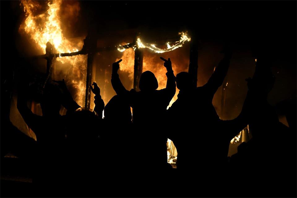 Ein vermummter Demonstrant streckt den Mittelfinger aus.Hameraldi Agolli/AP/dpa