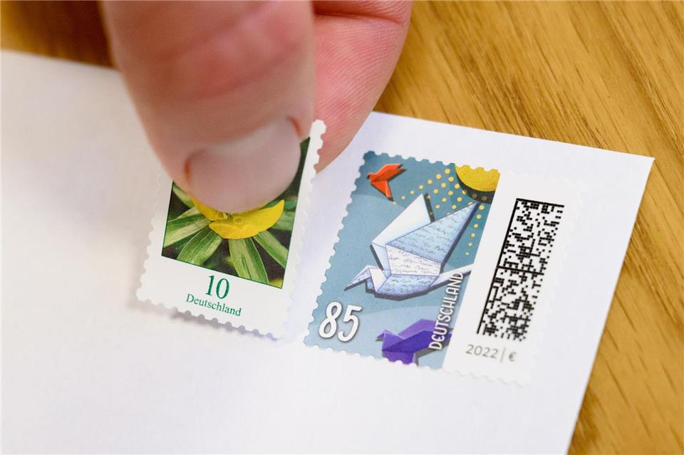 Eine 10-Cent-Briefmarke wird neben eine 85-Cent-Briefmarke geklebt (gestellte Szene). Julian Stratenschulte/dpa