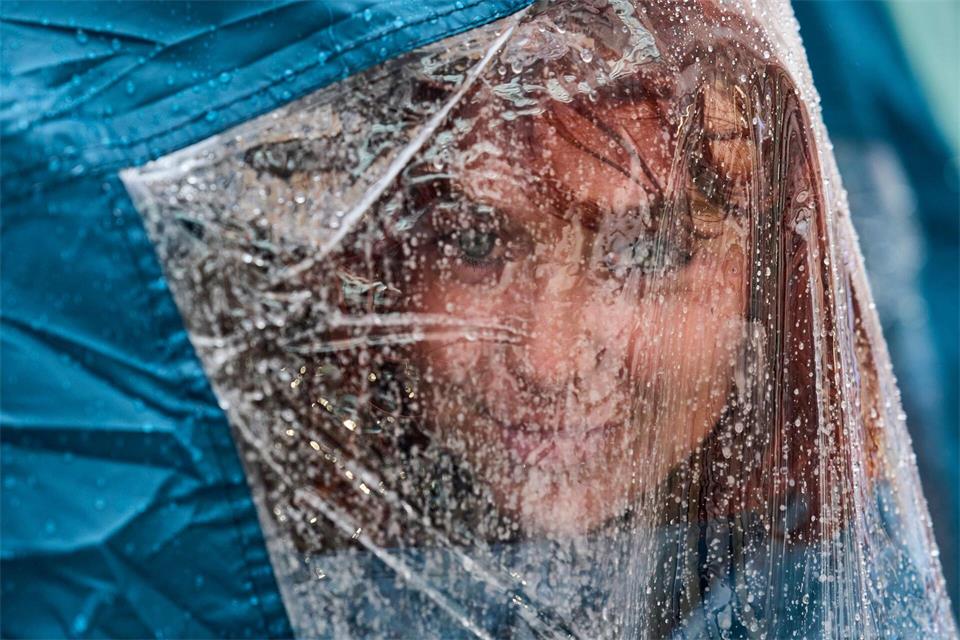 Eine Aktivistin blickt unter ihrer Regenkappe hervor, während sie bei starkem Regen auf dem Platz Puerta del Sol in Madrid an einem Protestcamp für das Recht auf Wohnen teilnimmt.Manu Fernandez/AP/dpa