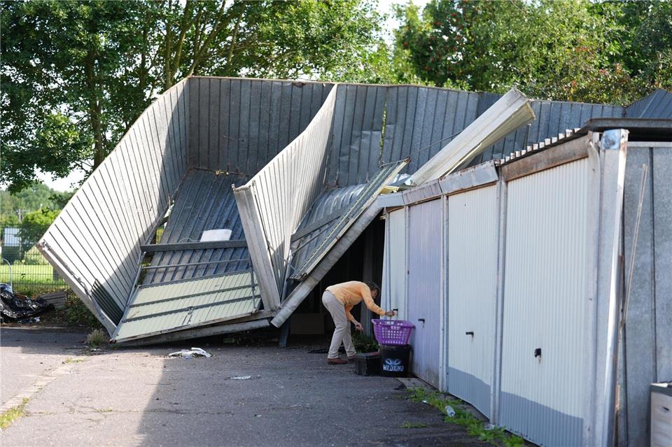 Eine Anwohnerin kontrolliert ihre unbeschädigte Garage neben den durch ein Unwetter zerborstenen und teils weggewehten Garagen.Marcus Brandt/dpa