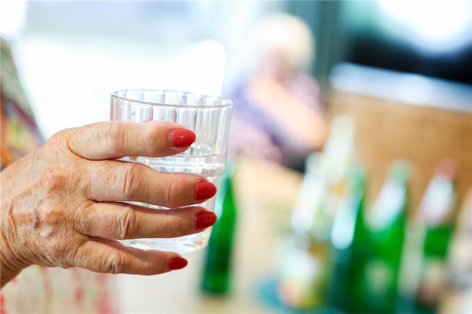 Eine Bewohnerin eines Seniorenheims hält bei sommerlichen Temperaturen ein Glas mit Wasser in ihrer Hand. (Symbolbild)Christoph Reichwein/dpa