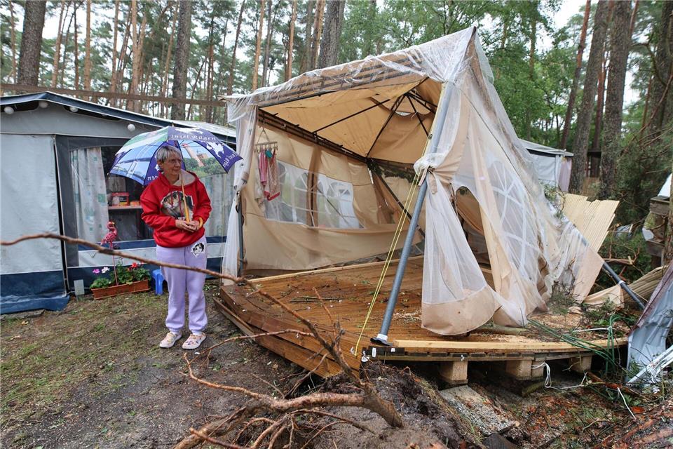Eine Dauercamperin steht fassungslos vor ihrem zerstörten Zelt-Pavillon. Matthias Bein/dpa