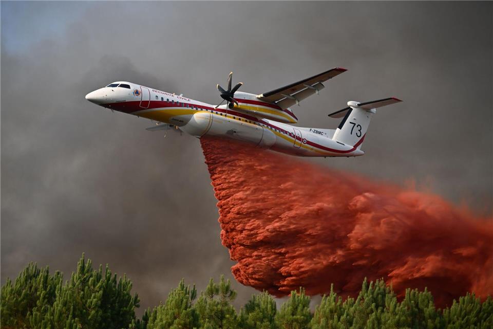 Eine De Havilland Canada Dash 8-400 versprüht Löschmittel, während sie bei den Waldbränden im Südwesten Frankreichs über einen Wald fliegt.Emma Da Silva/AP/dpa