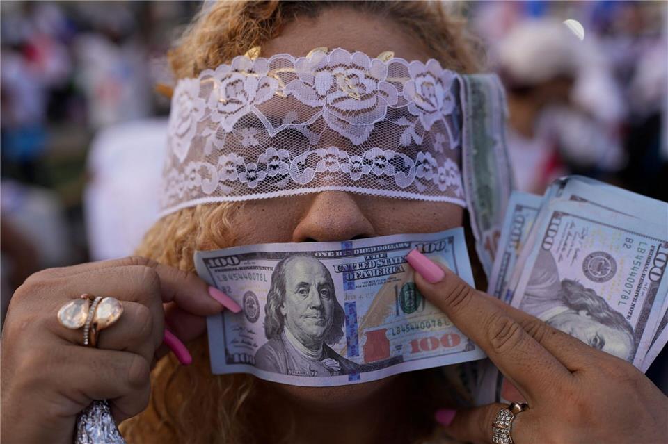 Eine Demonstrantin hält während einer Demonstration in Panama-Stadt gegen die Politik von Panamas Präsident Mulino eine falsche US-Banknote vor ihren Mund.Matias Delacroix/AP/dpa