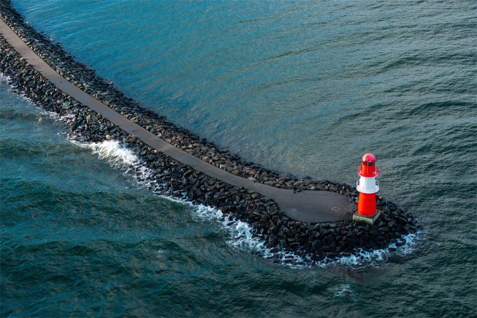 Eine Drohne macht Aufnahmen von der Ostmole an der Hafeneinfahrt in Warnemünde - die Küstenlinie soll künftig stärker auf Drohnenflüge überwacht werden. (Archivbild) Jens Büttner/dpa