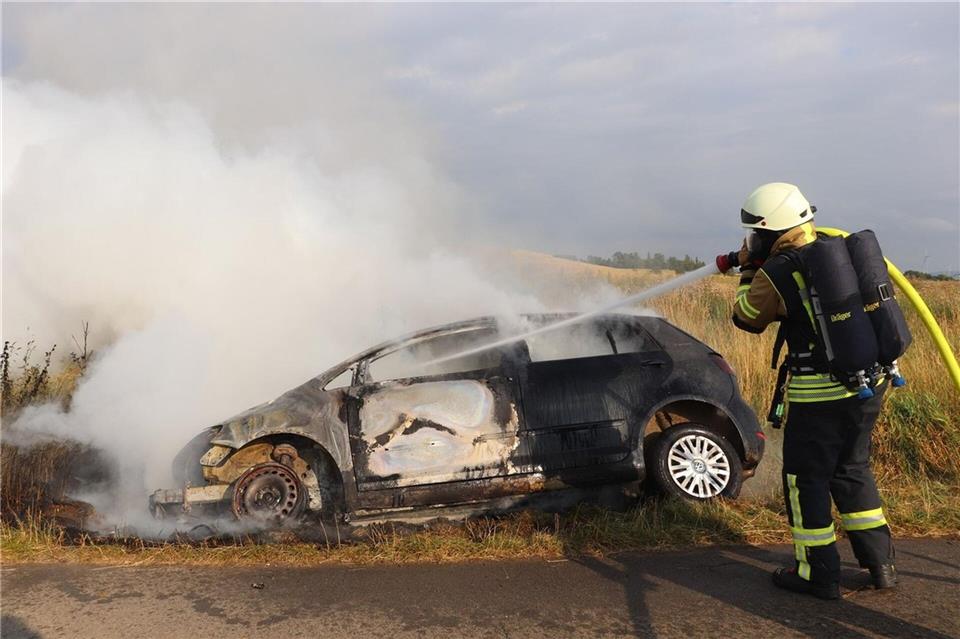 Eine Einsatzkraft der Feuerwehr löscht ein brennendes Auto, aus dem zuvor ein 82-Jähriger gerettet wurde.Kreispolizeibehörde Höxter/dpa