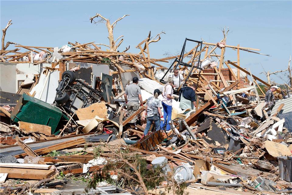 Eine Familie blickt nach einem Tornado durch die Trümmer ihres Hauses im Stadtteil Grayridge in Oklahoma.Alonzo Adams/AP/dpa