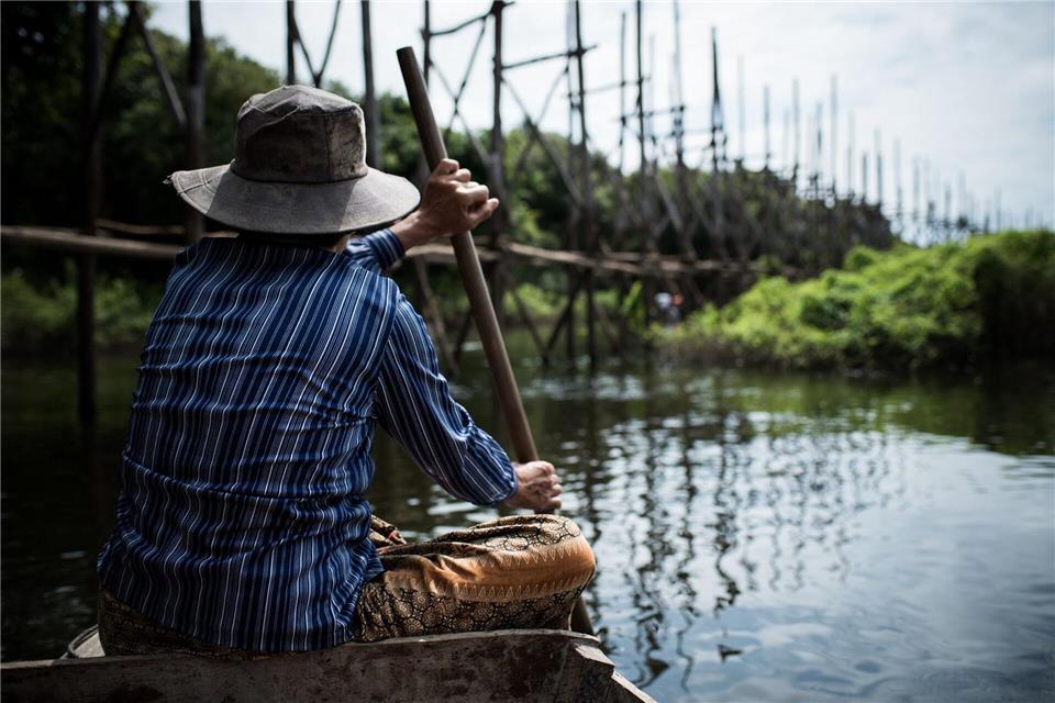 Eine Fischerin durchquert einen überfluteten Wald - während Regenzeit wächst der See immens.Zacharie Scheurer/dpa-tmn