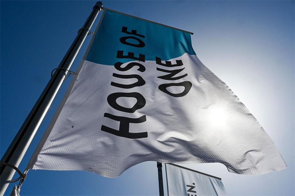 Eine Flagge weist auf das interreligiöse Projekt House of One in Berlin-Mitte hin. (Archivbild) Jens Kalaene/dpa
