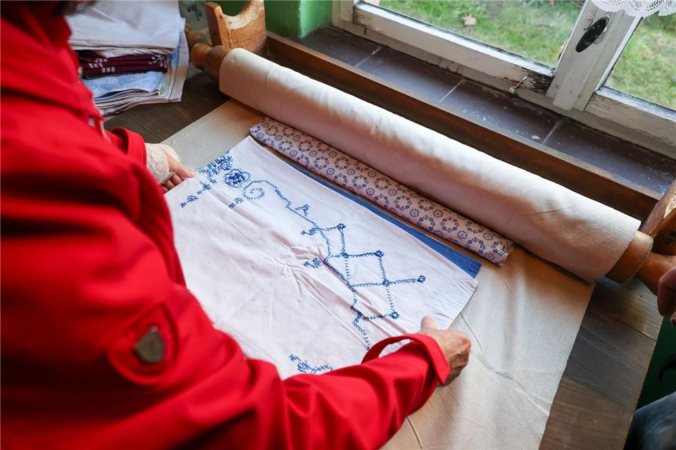 Eine Frau bereitet Wäsche für das Mangeln mit einer historischen Kaltmangel vor.Jan Woitas/dpa