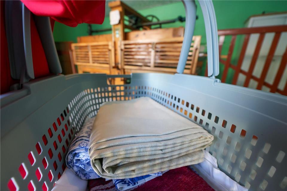 Eine Frau bringt Wäsche zum Mangeln. Dank historischer Technik sollen die Textilien nach dem Waschen wieder schön glatt werden.Jan Woitas/dpa