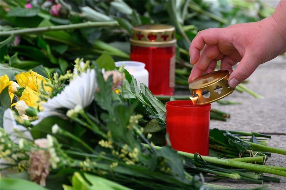 Eine Frau entzündet nach der  Amokfahrt mit zwei Todesopfern und drei Schwerverletzten am Gedenkort vor dem Paulinum der Universität eine Kerze. Hendrik Schmidt/dpa