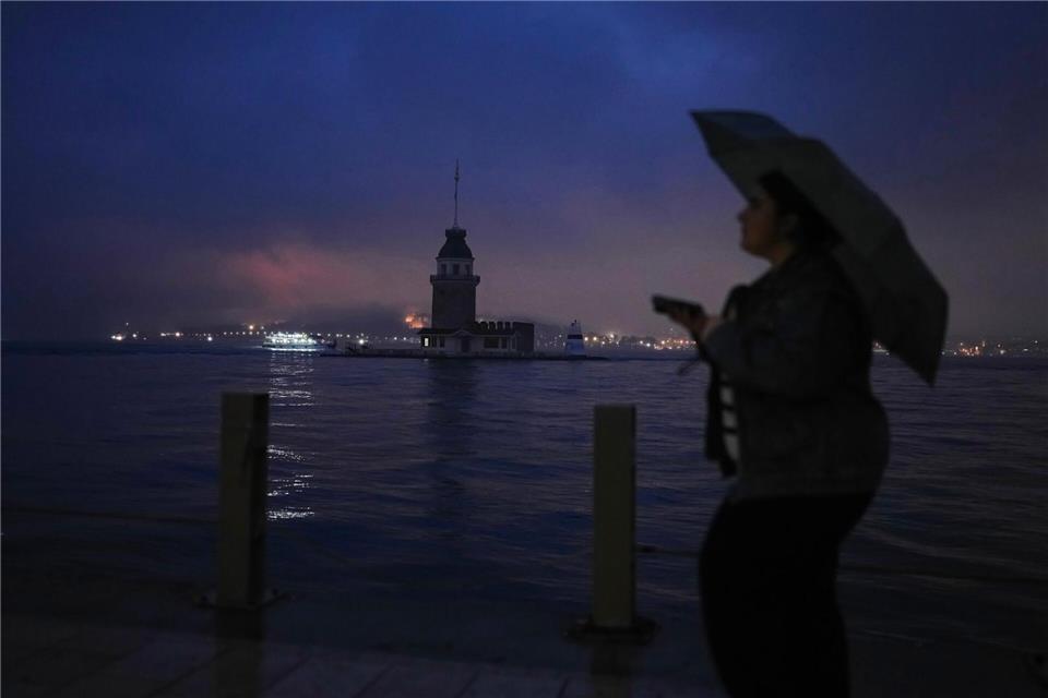 Eine Frau geht an einem regnerischen Tag in Istanbul am Jungfernturm am Bosporus vorbei.Francisco Seco/AP/dpa