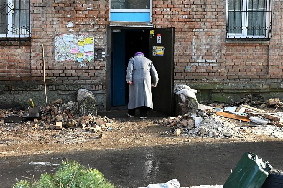 Eine Frau geht in ein beschädigtes Haus.Aleksandr Gusev/SOPA Images via ZUMA Press Wire/dpa