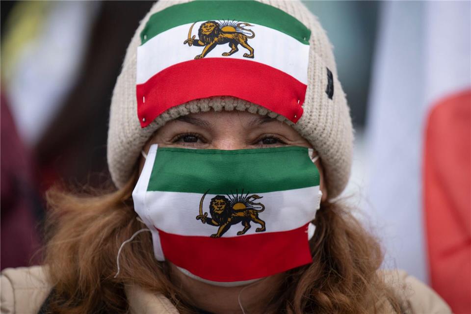 Eine Frau hat bei der Demo vor dem US-Generalkonsulat in Frankfurt die alte iranische Flagge mit dem Löwen getragenBoris Roessler/dpa