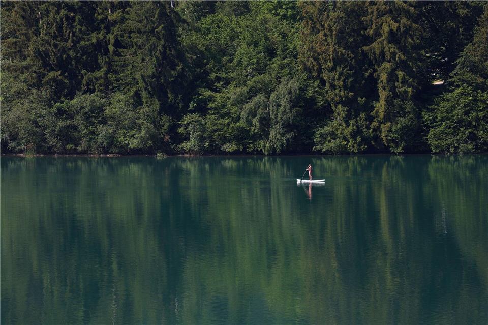 Eine Frau paddelt auf einem Stand-up-Paddle-Board über den Forggensee. Karl-Josef Hildenbrand/dpa