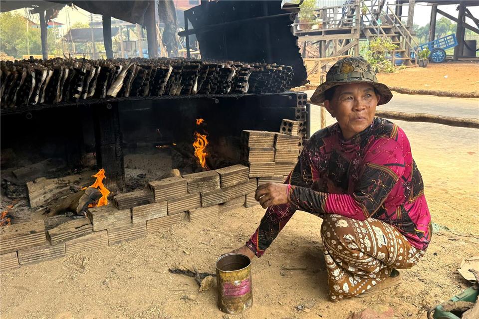 Eine Frau räuchert im See gefangenen Fisch nach einer uralten Technik über Holzkohle - und macht ihn so haltbar.Carola Frentzen/dpa