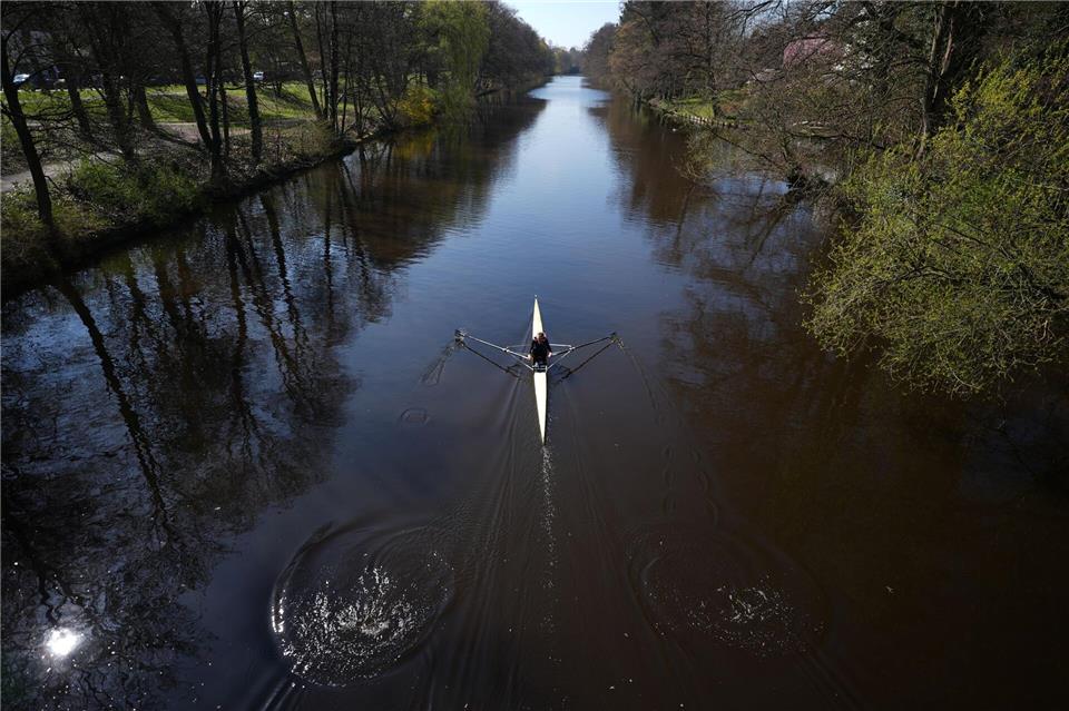 Eine Frau rudert mit ihrem Kajak bei schönstem Sonnenschein auf der Alster in Richtung Außenalster.Marcus Brandt/dpa