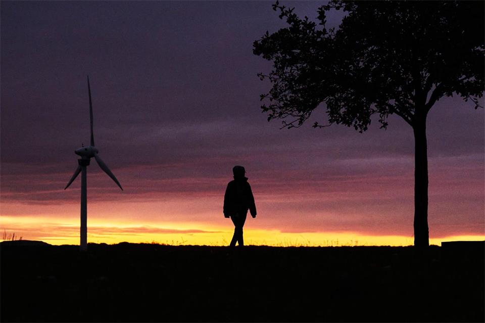 Eine Frau spaziert vor der vom Sonnenaufgang verfärbten morgendlichen Wolkenkulisse bei Hannover. Julian Stratenschulte/dpa