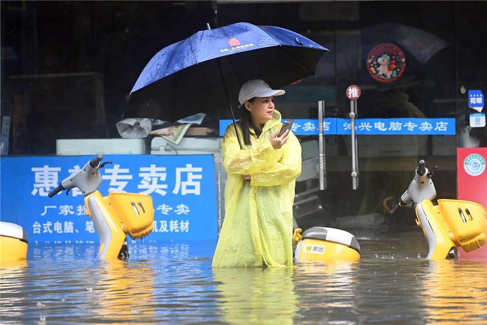 Eine Frau steht in Qinzhou auf einer mit Wasser vollgelaufenen Straße.Zhang Ailin/XinHua/dpa