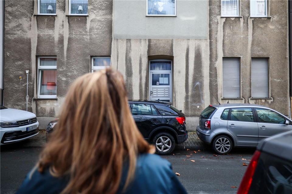 Eine Frau steht vor dem Mehrfamilienhaus, in dem ein zwölfjähriges Mädchen bei einem Polizeieinsatz durch Schüsse lebensgefährlich verletzt worden.Christoph Reichwein/dpa