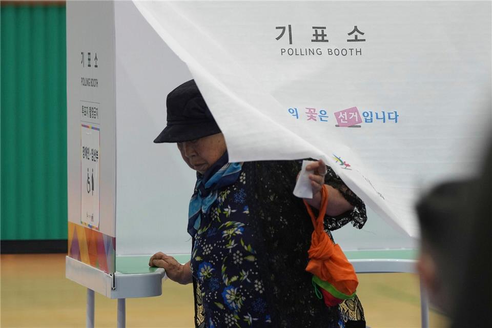 Eine Frau verlässt eine Wahlkabine, um ihre Stimme bei der Präsidentschaftswahl in Südkorea in einem Wahllokal abzugeben.Lee Jin-man/AP/dpa