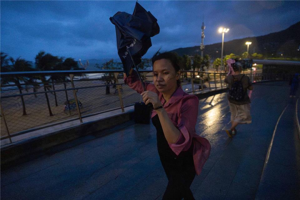 Eine Frau versucht, nach dem Super-Taifun Ragasa in Shenzhen in der südchinesischen Provinz Guangdong einen Regenschirm im Wind zu öffnen.Ng Han Guan/AP/dpa