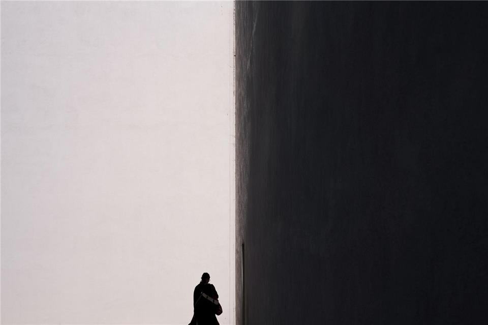 Eine Frau zeichnet sich als Silhouette vor der sonnenbeschienenen Fassade eines Gebäudes in in Kalifornien ab.Jae C. Hong/AP/dpa