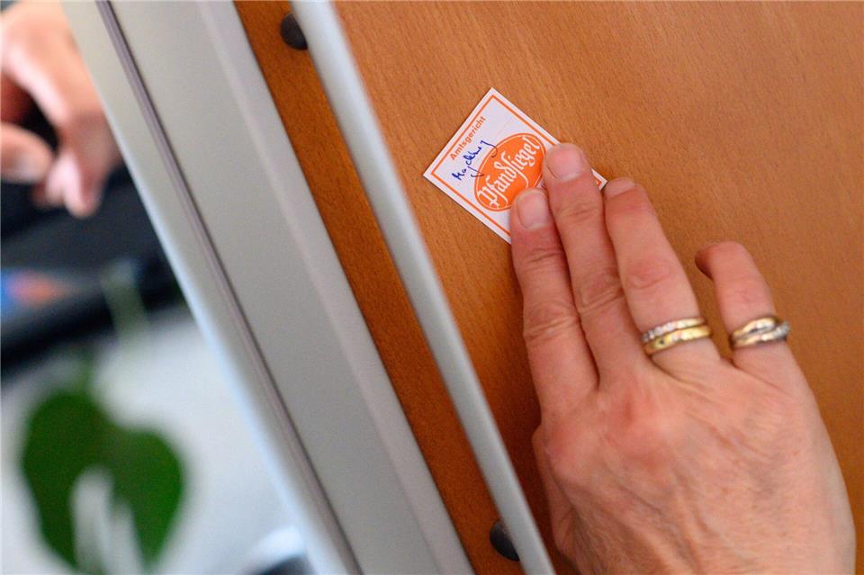 Eine Gerichtsvollzieherin klebt ein Pfandsiegel auf ein technisches Gerät. (Symbolbild) Klaus-Dietmar Gabbert/dpa