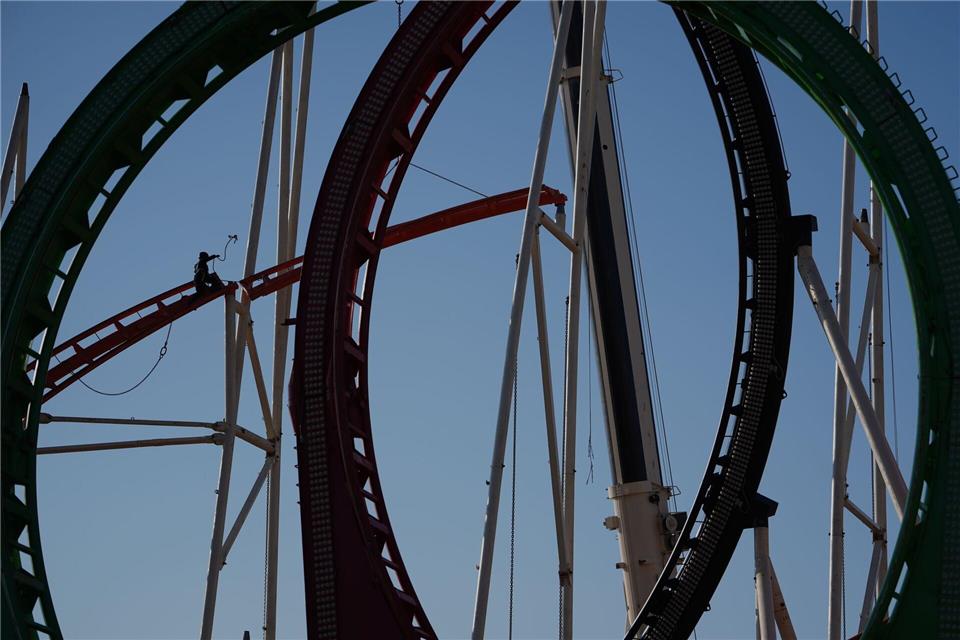Eine Höhenkletterin nimmt in luftiger Höhe während der Aufbauarbeiten des Frühlingsdoms eine Schiene der Achterbahn auf dem Heiligengeistfeld in Hamburg entgegen.Marcus Brandt/dpa