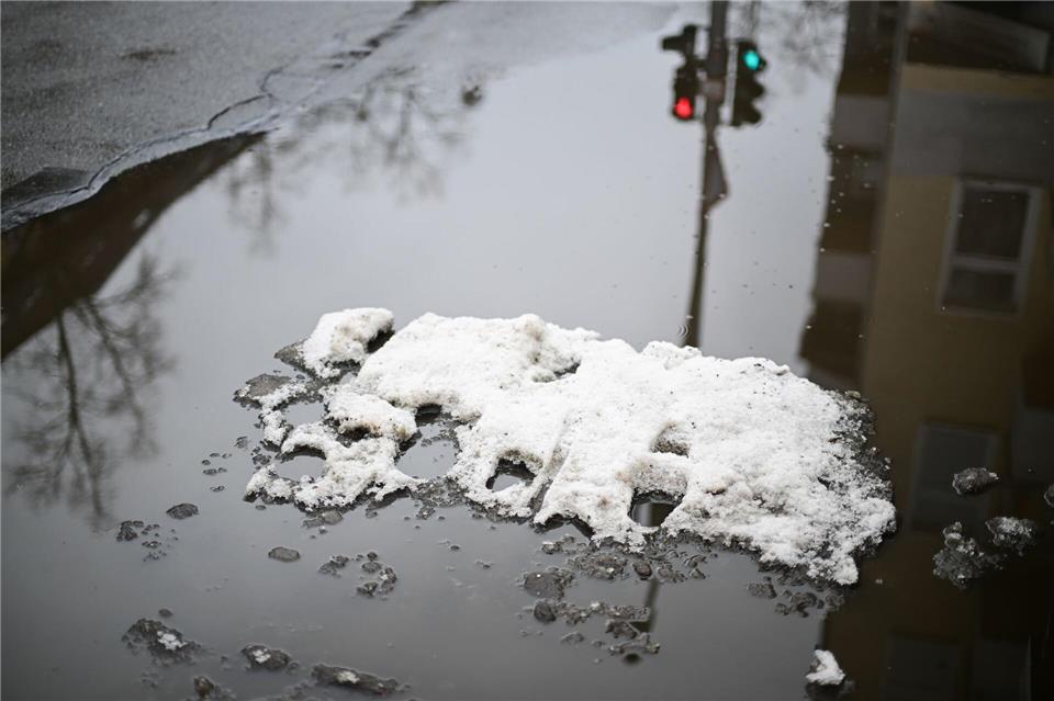 Eine Insel von Schnee und Eis liegt in einer Pfütze.Sebastian Christoph Gollnow/dpa