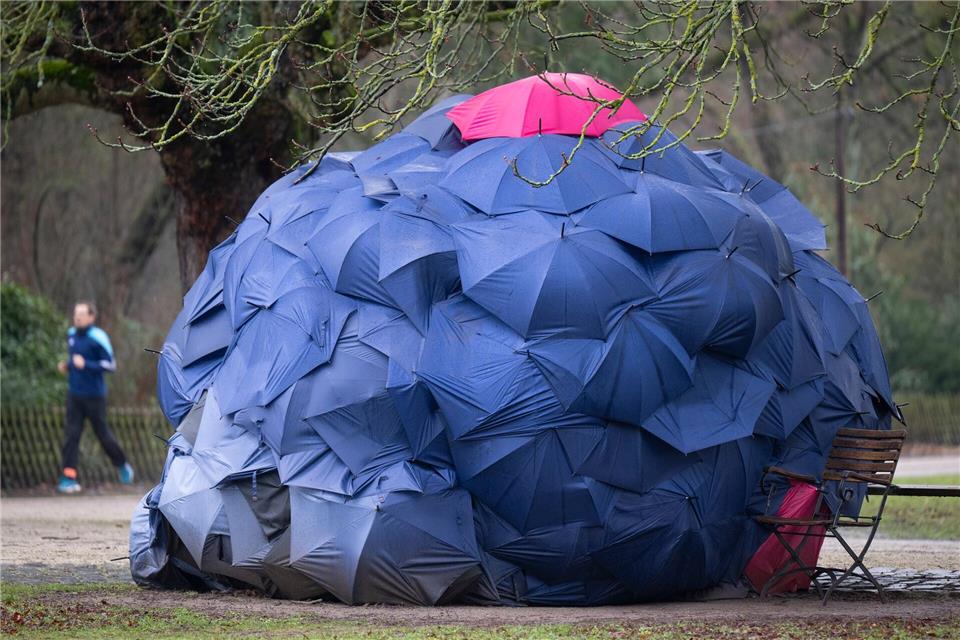 Eine Konstruktion aus Schirmen: Eine Frau hat sich bei einstelligen Temperaturen eine provisorische Bleibe in einem Park gebaut.Boris Roessler/dpa