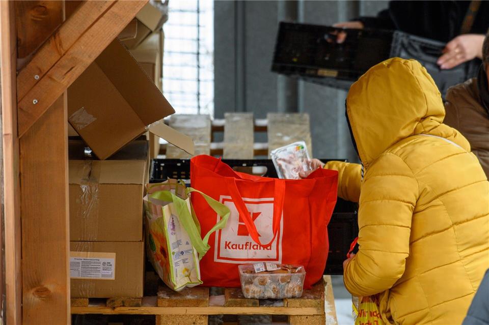 Eine Kundin der Tafel in Zerbst packt Lebensmittel in ihre Tasche.Klaus-Dietmar Gabbert/dpa