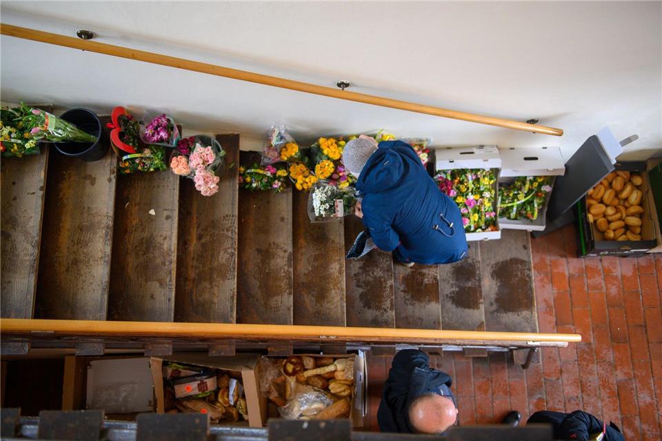 Eine Kundin der Tafel sucht sich im Treppenhaus einen Blumenstrauß aus.Klaus-Dietmar Gabbert/dpa
