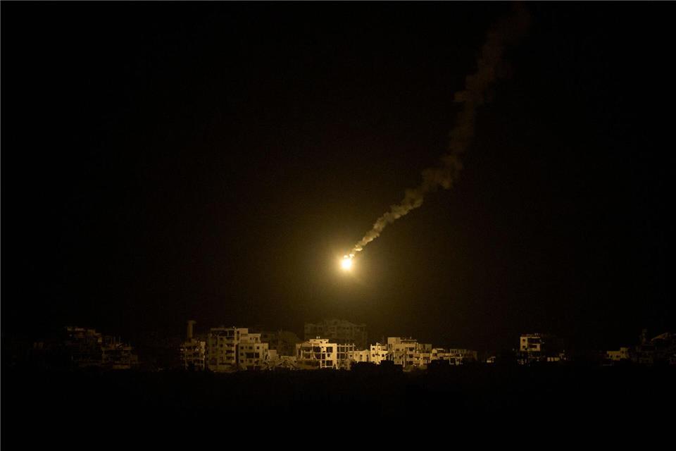 Bilder des Tages Eine Leuchtrakete der israelischen Armee fliegt über Gebäuden, die während der israelischen Boden- und Luftoperationen im nördlichen Gazastreifen zerstört wurden.Leo Correa/AP/dpa
