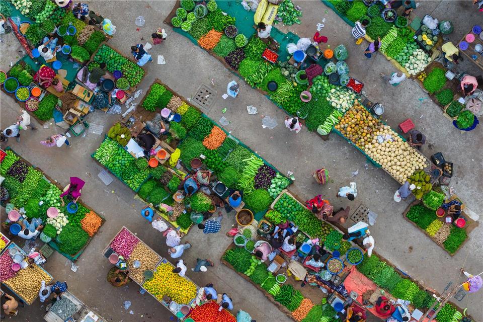 Eine Luftaufnahme zeigt das lebhafte Treiben auf einem Gemüsemarkt in Ahmedabad in Indien, wo Verkäufer frische Produkte anordnen und Kunden sich durch die engen Marktgassen bewegen.Saurabh Sirohiya/ZUMA Press Wire/dpa