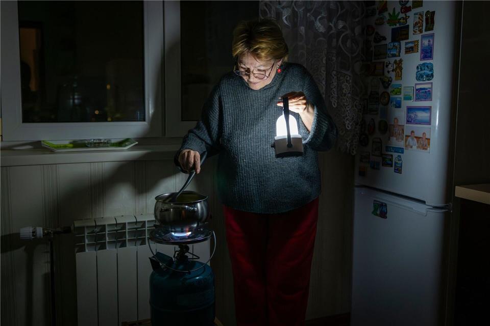 Eine Mutter kocht auf einem Gasbrenner nach einem Stromausfall in Kiew durch einen russischen Angriff.Dan Bashakov/AP/dpa