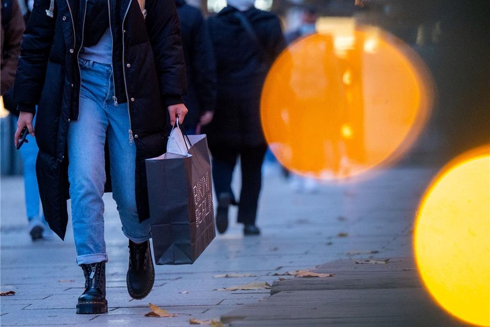 Eine Passantin geht mit einer Einkaufstasche durch die Innenstadt.