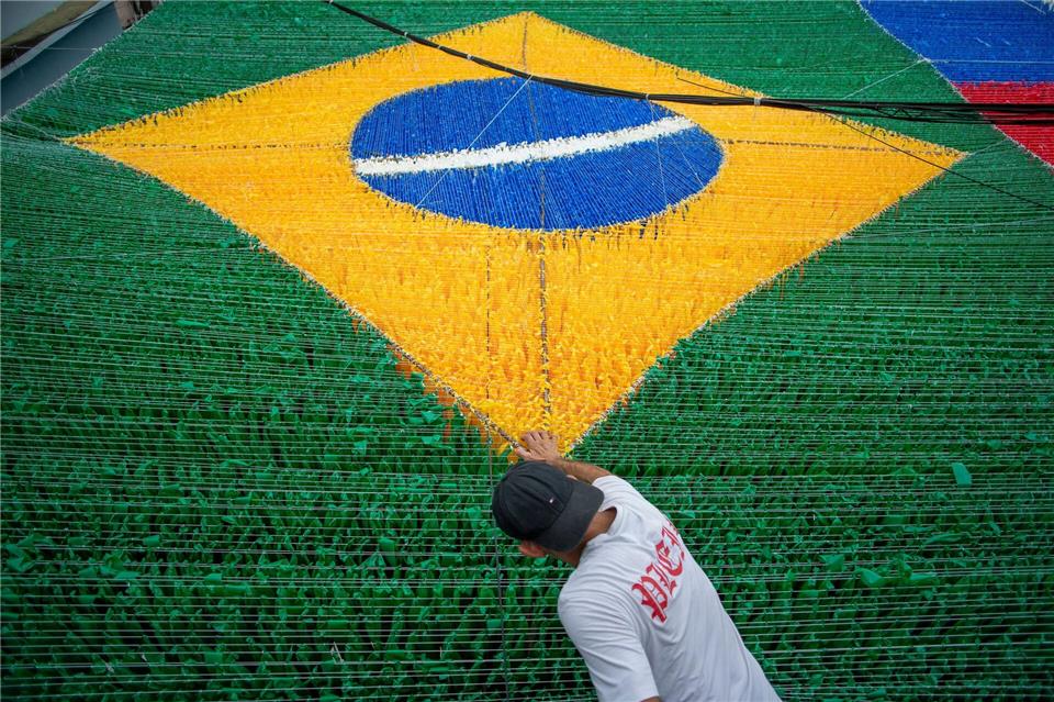 Eine Person gibt der hängenden Dekoration zur Feier der Fußballweltmeisterschaft 2026 auf der Rua 03 im Viertel Alvorada in Manaus, der Hauptstadt des brasilianischen Bundesstaates Amazonas, den letzten Schliff.Suamy Beydoun/dpa