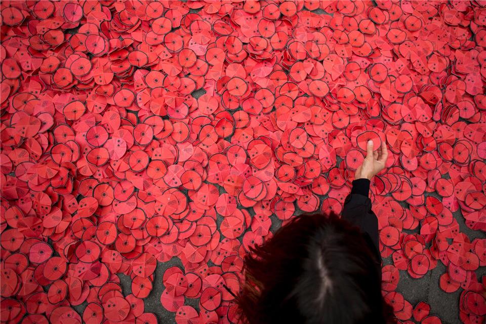 Eine Person hebt eine Papiermohnblume auf, die während einer Kundgebung gegen den Gaza-Krieg vor dem spanischen Außenministerium in Madrid auf dem Boden liegt. Luis Soto/SOPA Images via ZUMA Press Wire/dpa