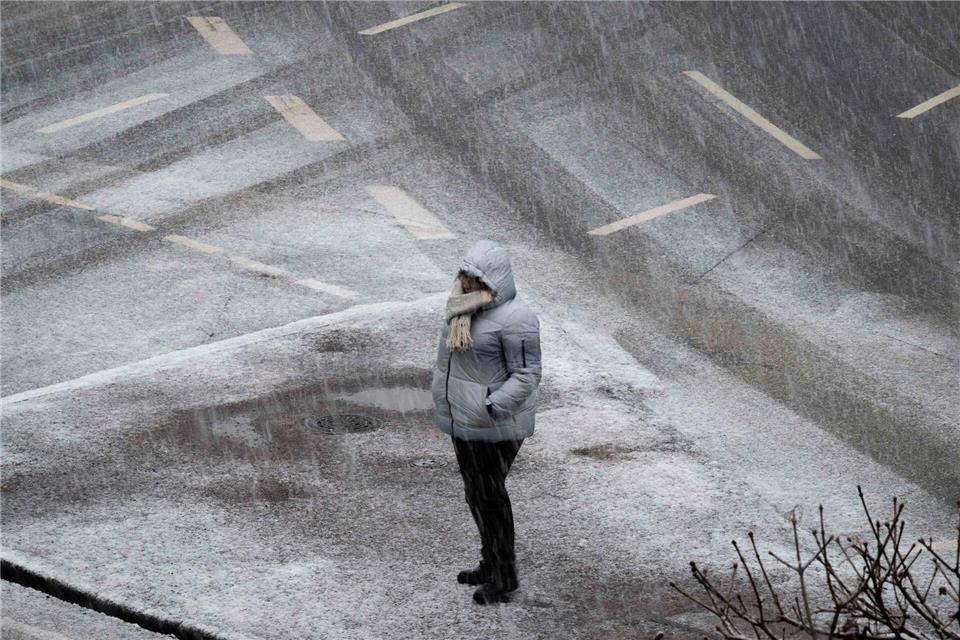 Eine Person steht bei starkem Schneefall an einer Kreuzung in Frankfurt. Boris Roessler/dpa