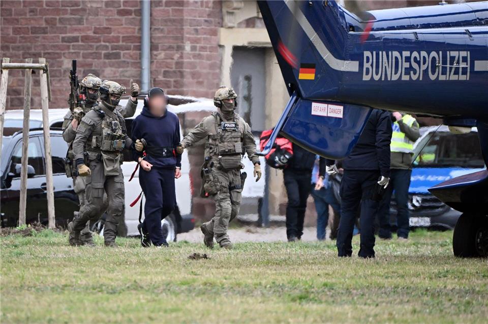 Eine Person wird von Polizeibeamten zu einem Hubschrauber gebracht.Uli Deck/dpa