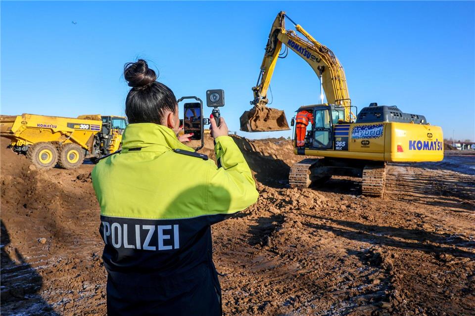 Eine Polizistin filmt einen Bagger beim Spatenstich auf dem Gelände des neuen Landeskriminalamts.Peter Gercke/dpa