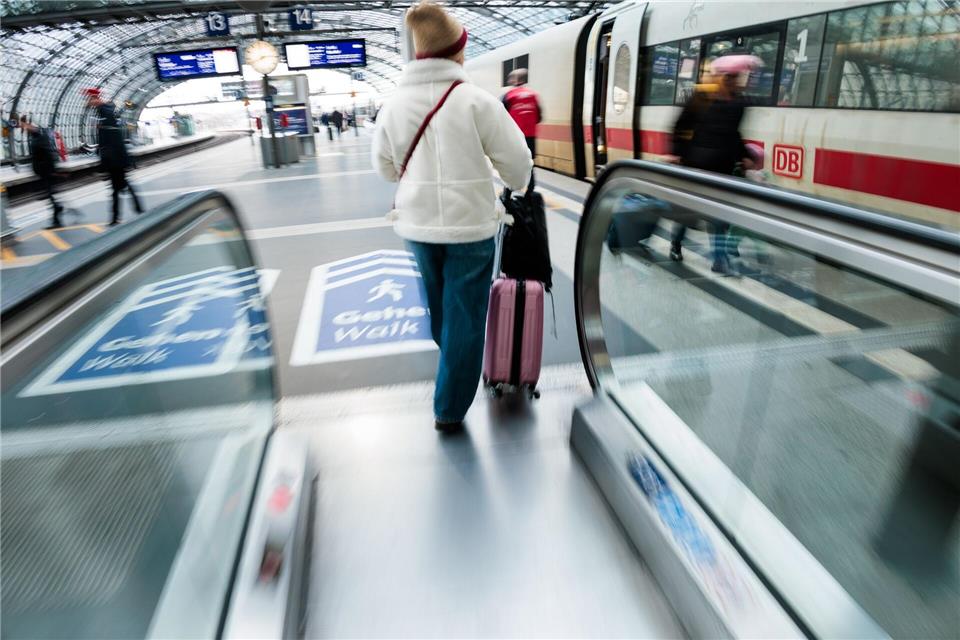 Eine Reisende fährt am Berliner Hauptbahnhof mit ihrem Koffer eine Rolltreppe zum Bahnsteig hinauf.Carsten Koall/dpa