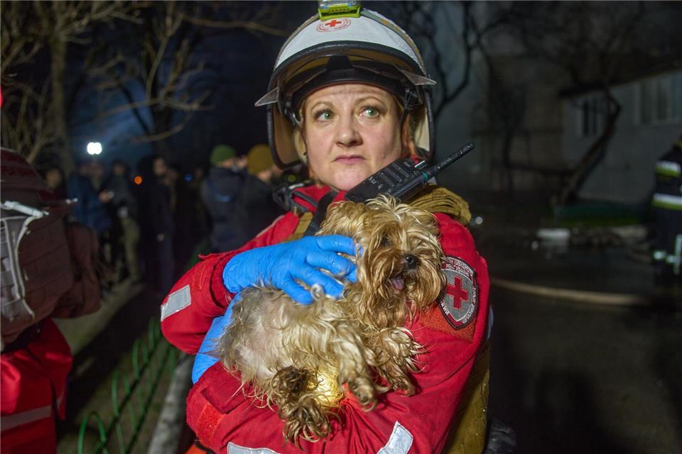 Eine Retterin hält einen geretteten Hund nach dem Einschlag einer russischen Rakete in ein mehrstöckiges Wohnhaus außerhalb von Kiew.Efrem Lukatsky/AP/dpa