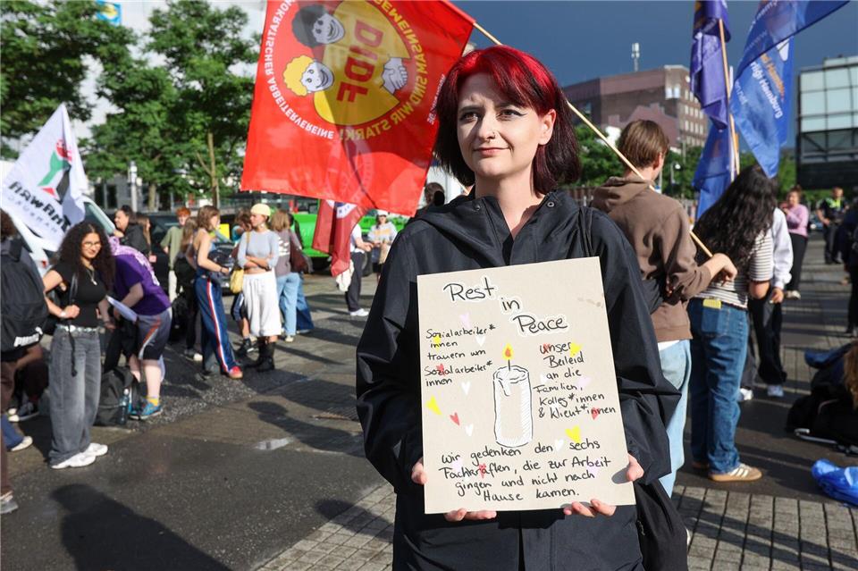 Eine Sozialarbeiterin hält ein Pappschild. Darauf steht etwa „Rest in Peace“ und „Sozialarbeiter*innen trauern um Sozialarbeiter*innen“.Bodo Marks/dpa