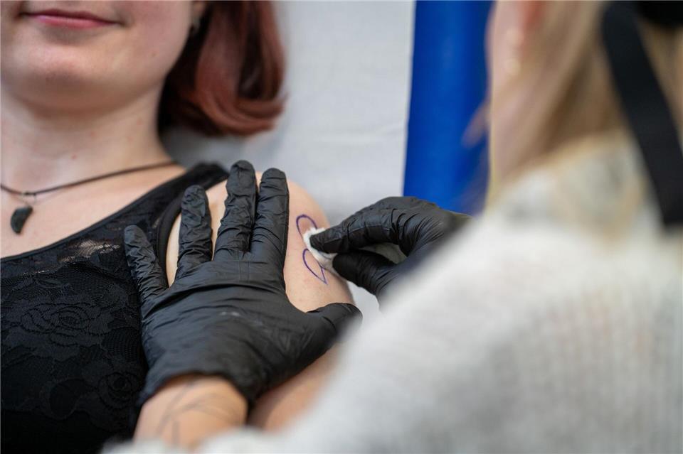 Eine Tätowiererin bei Aktionstag des Uniklinik Münster tätowiert das Symbol der Organspende auf einen Oberarm.Max Lametz/dpa