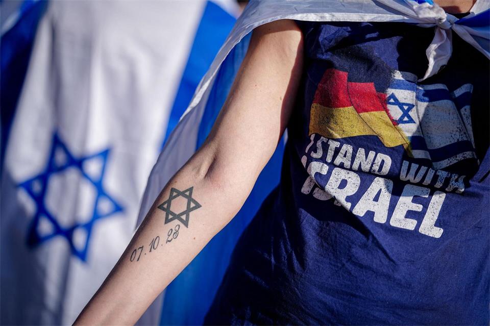 Eine Teilnehmerin der Gedenkveranstaltung zeigt ihr Tattoo mit dem Datum 07.10.23 neben einem DavidsternKay Nietfeld/dpa